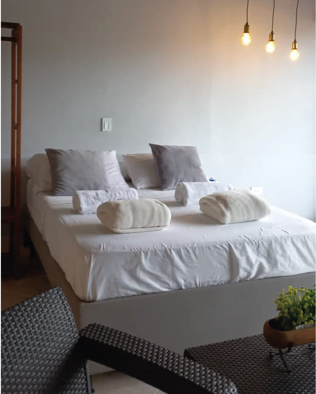 Cama doble con ropa de cama blanca reflejada en el espejo del loft
